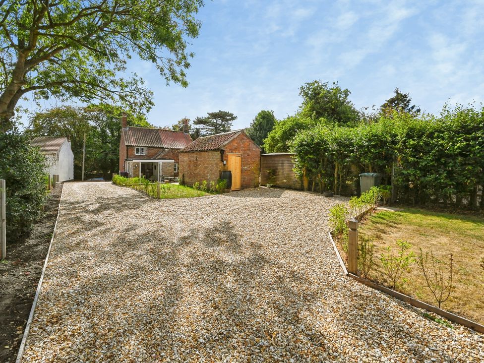 A garden with a gravel driveway and brick building at Susans Cottage in 