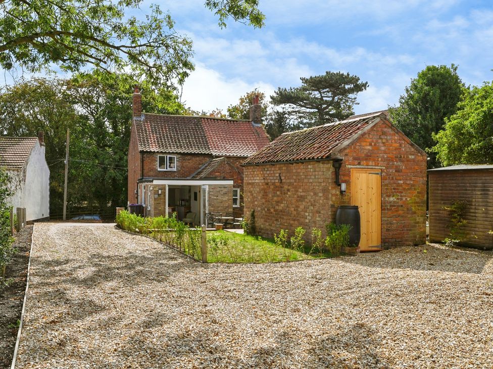A house with a brick garage and gravel drive at Susans Cottage