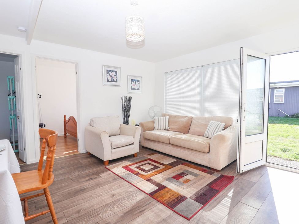 A living room with a sofa, armchair and rug at 122 Norton Park, Dartmouth