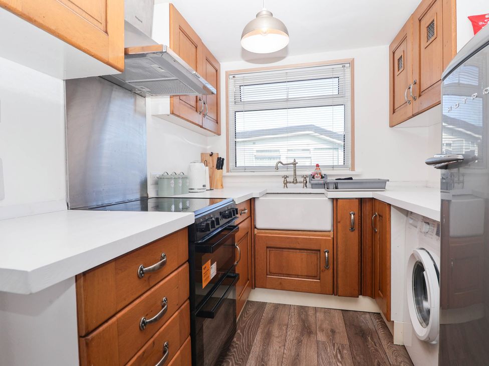 A kitchen with a sink, stove, and washing machine at 122 Norton Park in Dartmouth