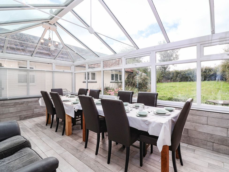 A conservatory with a dining table and chairs at Herriotts Bridge Cottage in Bristol