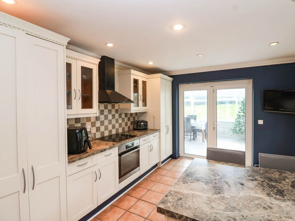 A kitchen with cabinets, stove, and table at Herriotts Bridge Cottage in Bristol