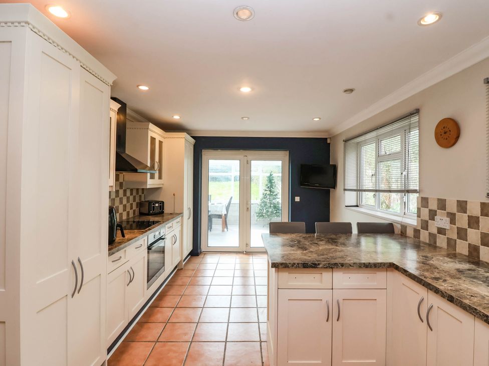 A kitchen with cabinets and a sliding door at Herriotts Bridge Cottage in Bristol