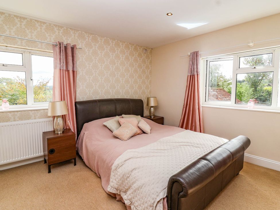 A bedroom with a bed and windows at Herriotts Bridge Cottage in Bristol