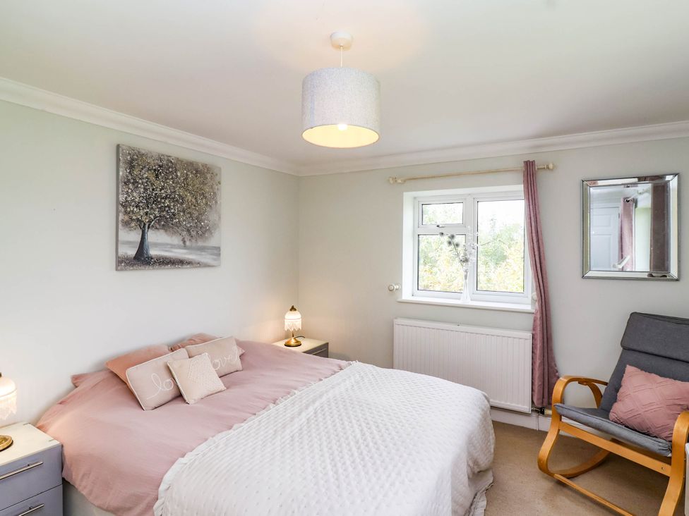 A bedroom with a bed and a rocking chair at Herriotts Bridge Cottage in Bristol
