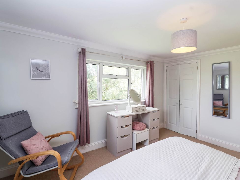 A bedroom with a bed, mirror, and window at Herriotts Bridge Cottage in Bristol