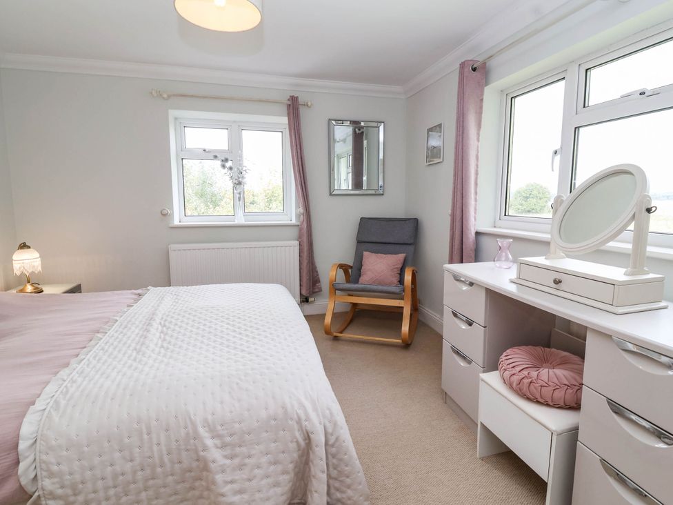A bedroom with a bed, dresser, and chair at Herriotts Bridge Cottage, Bristol