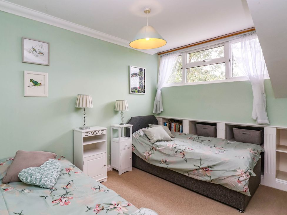 A bedroom with two beds and a side table at Herriotts Bridge Cottage in Bristol