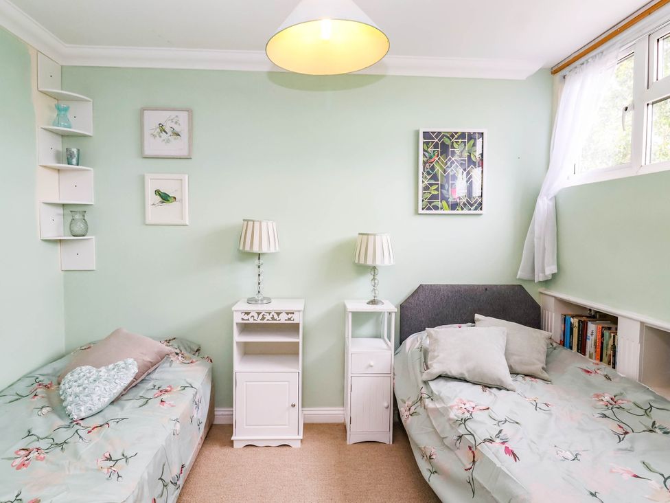 A bedroom with two beds and bedside tables at Herriotts Bridge Cottage in Bristol