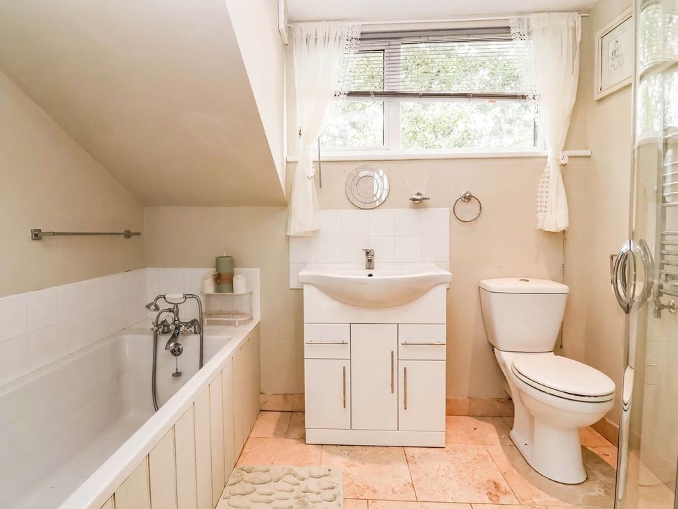 A bathroom with a bathtub, sink, and toilet at Herriotts Bridge Cottage in Bristol