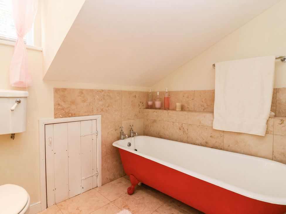 A bathroom with a red bathtub and sink at Herriotts Bridge Cottage in Bristol