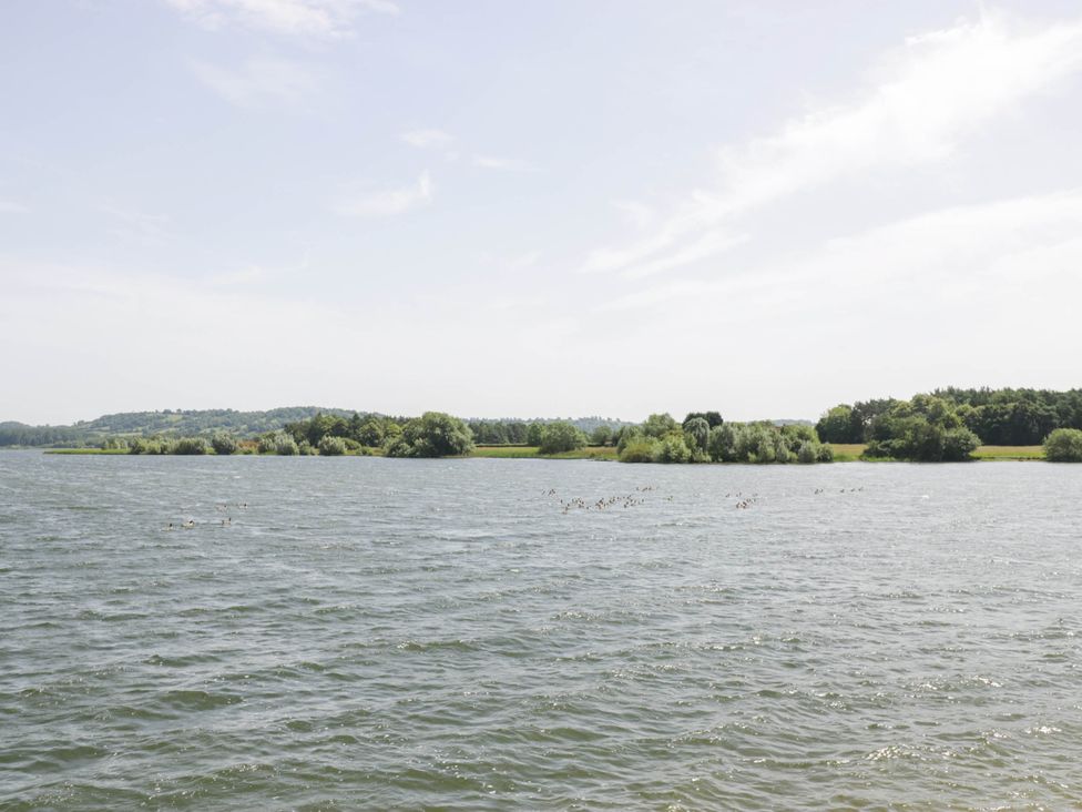 A lake with trees and hills in the background at Herriotts Bridge Cottage in Bristol