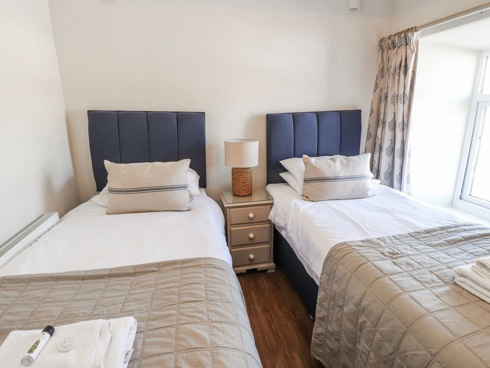 A bedroom with twin beds and a nightstand at Hen Blas in Pwllheli
