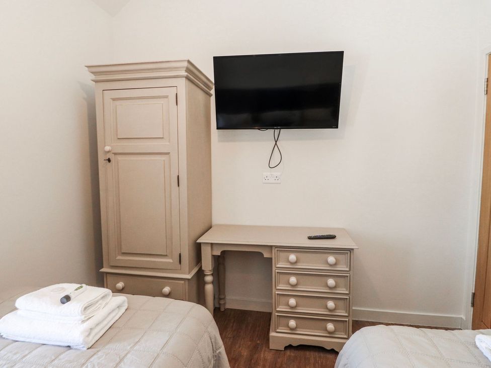 A bedroom with a wardrobe, television, and desk at Hen Blas in Pwllheli