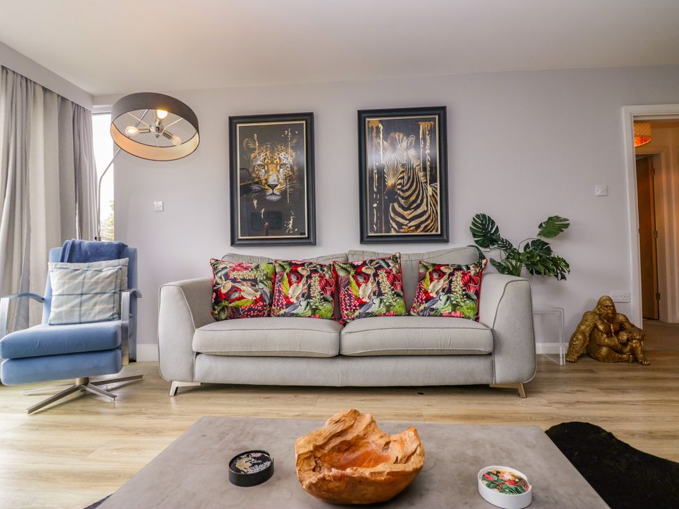 A living room with a sofa, armchair, and wall art at 10 Rayrigg Rise Bowness-On-Windermere