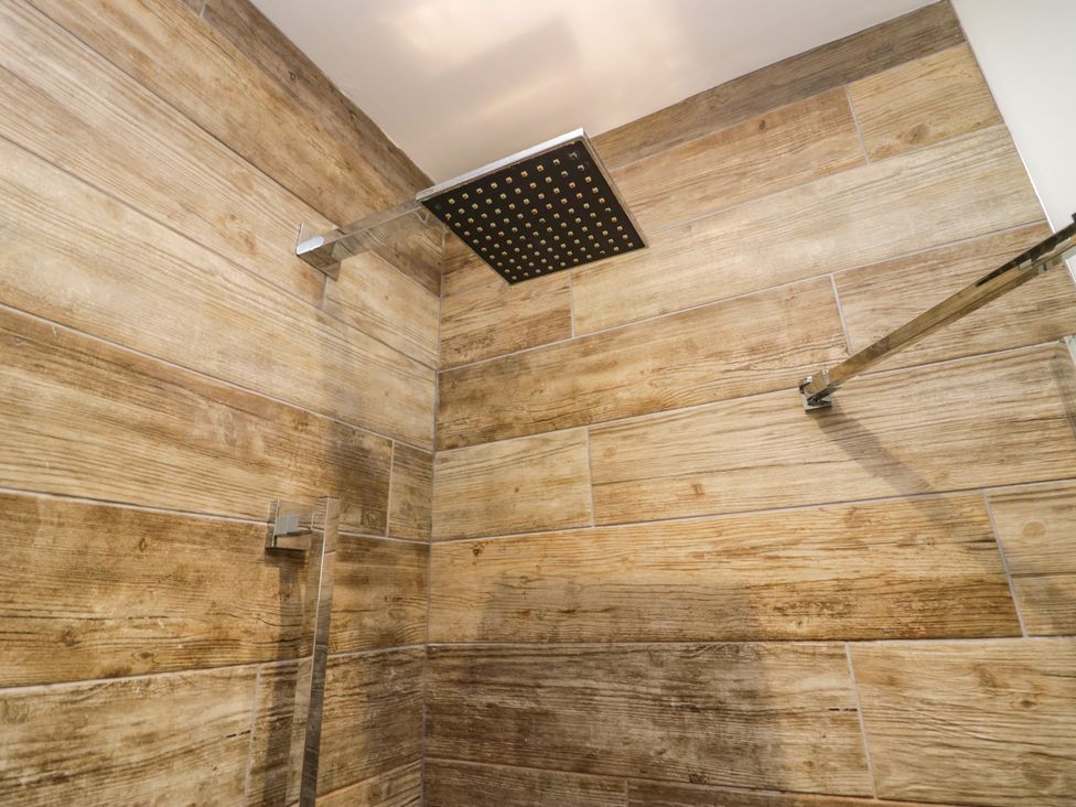 A shower with a square shower head and wooden panel wall at 10 Rayrigg Rise Bowness-On-Windermere