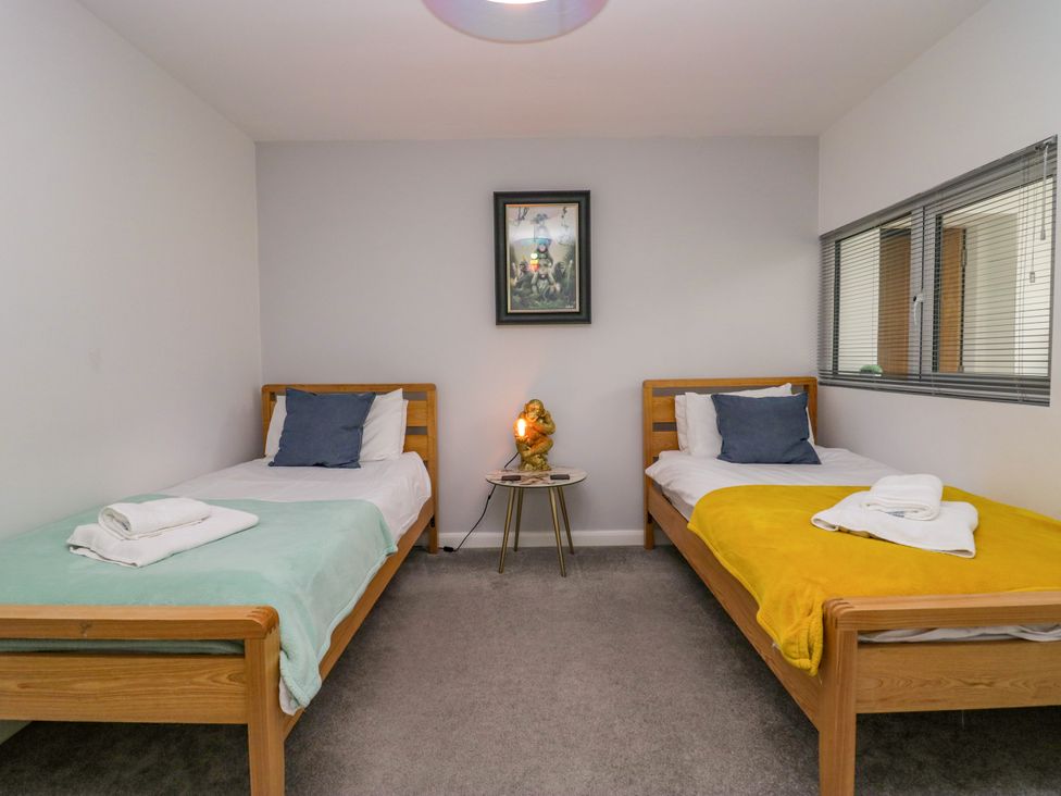 A bedroom with two beds and a nightstand at 10 Rayrigg Rise Bowness-On-Windermere