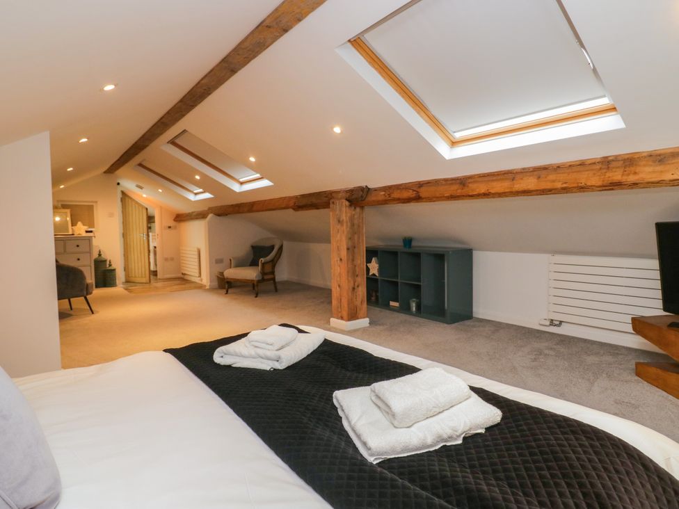 A loft with a bed, skylights, and a shelving unit at 10 Rayrigg Rise Bowness-On-Windermere