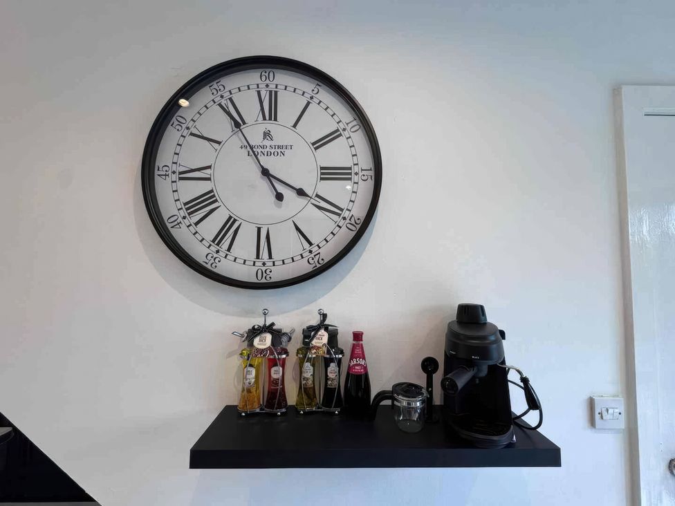A kitchen with a clock and coffee equipment at 11 Radclyffe Mews in Salford