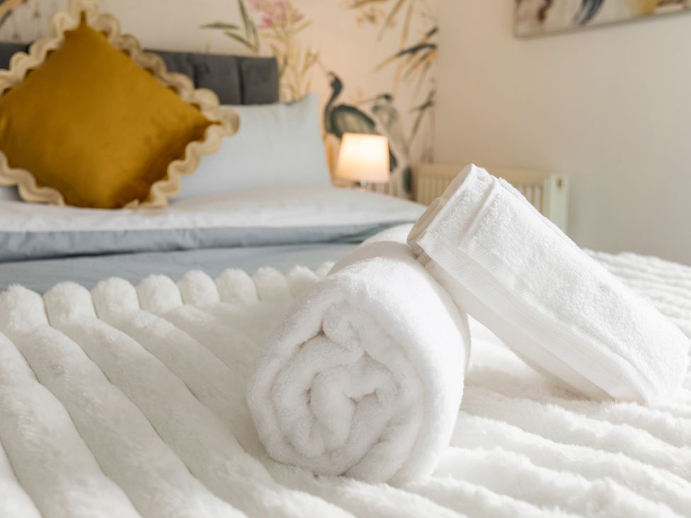 A bedroom with towels and a cushion on the bed at 11 Radclyffe Mews Salford