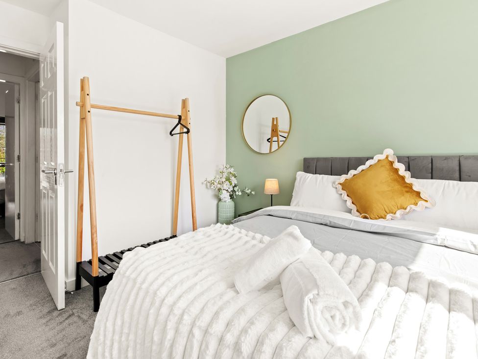 A bedroom with a bed, hanging rack, and mirror at 11 Radclyffe Mews in Salford