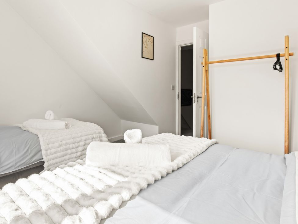 A bedroom with two beds and a clothes rack at 11 Radclyffe Mews, Salford