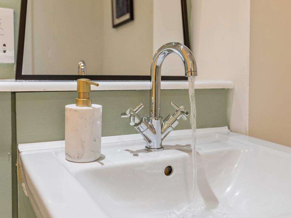 A sink with a faucet running water and a soap dispenser at 11 Radclyffe Mews, Salford