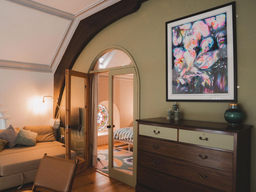 A bedroom with a sofa, dresser, and a painting at Chapel of Arts in Criccieth