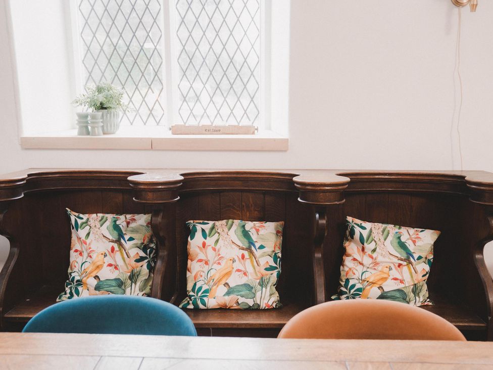 A living room with a wooden sofa and cushions at Chapel of Arts in Criccieth