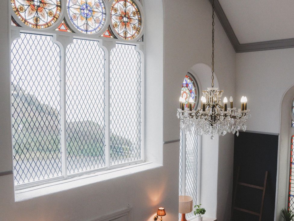 A room with a chandelier and stained glass windows at Chapel of Arts in Criccieth