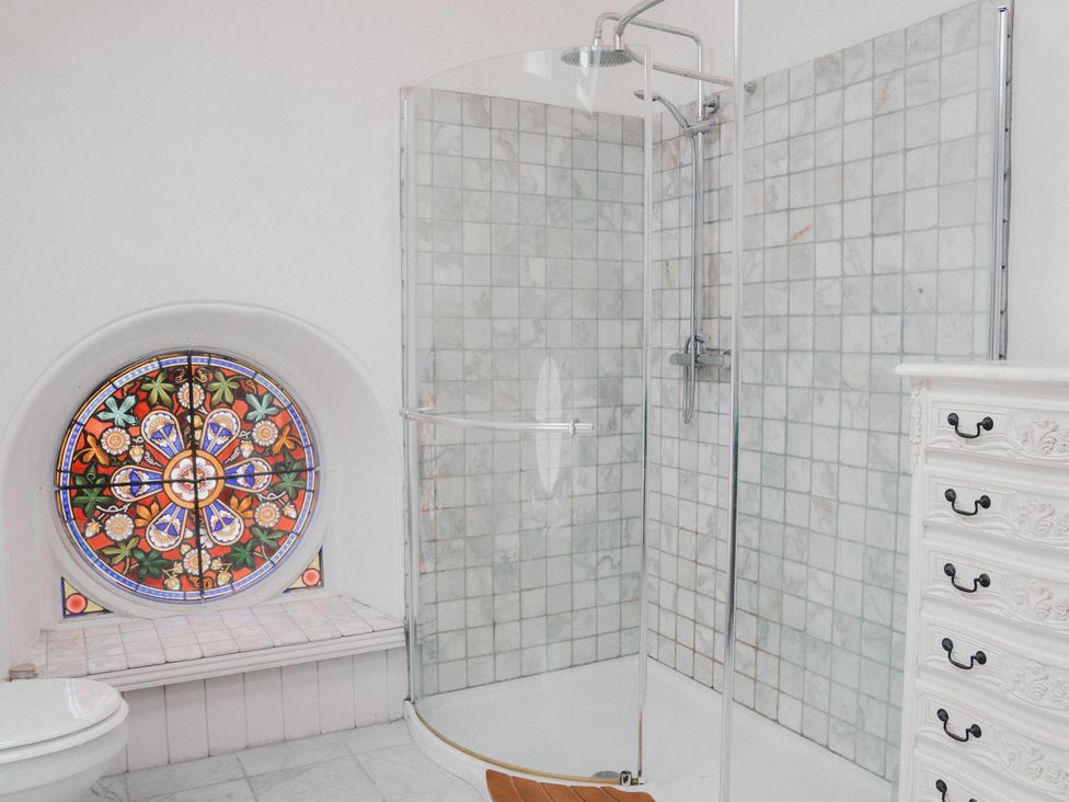 A bathroom with a shower and stained glass window at Chapel of Arts in Criccieth