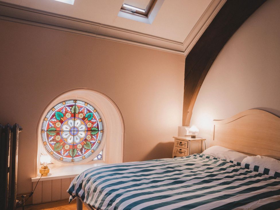 A bedroom with a bed and a stained glass window at Chapel of Arts in Criccieth