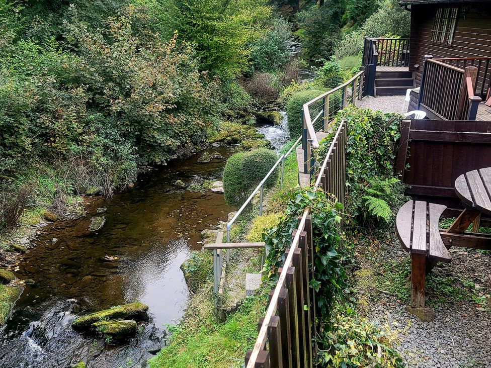 An outdoor area with a stream and seating at River Lodge in Lynbridge near Lynmouth