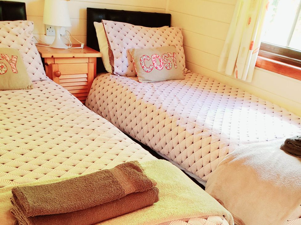 A bedroom with two beds and a bedside table at River Lodge in Lynbridge near Lynmouth