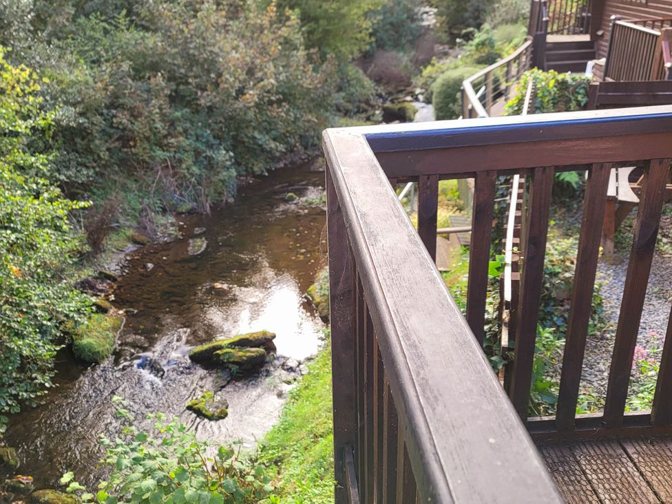 A view of a stream and wooden railing at River Lodge in Lynbridge near Lynmouth