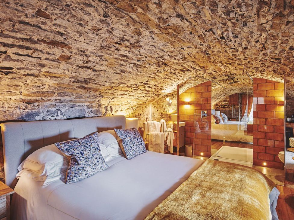 A bedroom with a stone wall and a bed at The Vault Hotel Room in Gileston near St Athan