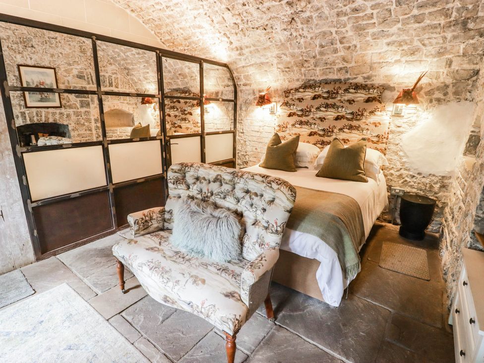 A bedroom with a bed and armchair at The Bakery Hotel Room in Gileston near St Athan