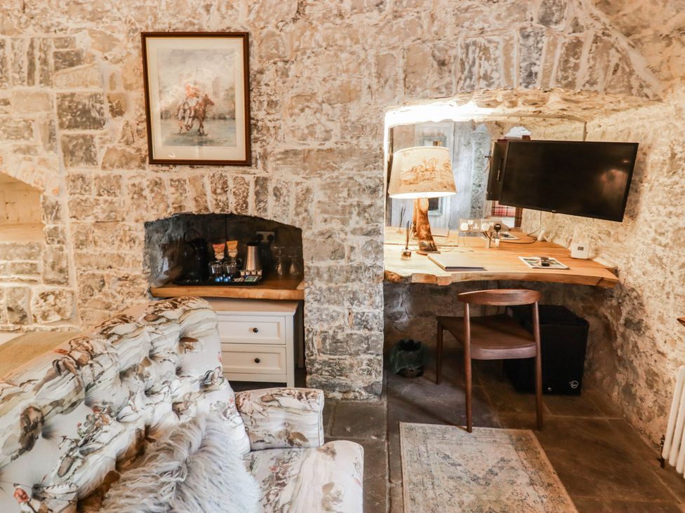 A room with a sofa and a desk with a television and coffee machine at The Bakery Hotel Room Gileston near St Athan