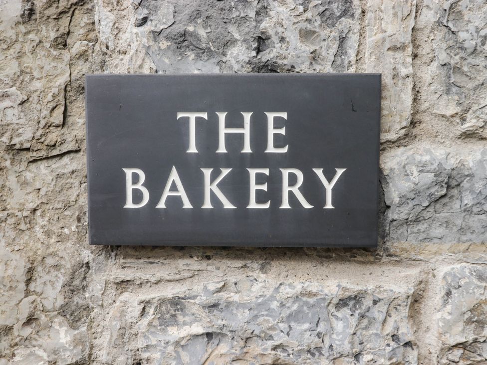 A sign that reads The Bakery on a stone wall at The Bakery Hotel Room in Gileston near St Athan