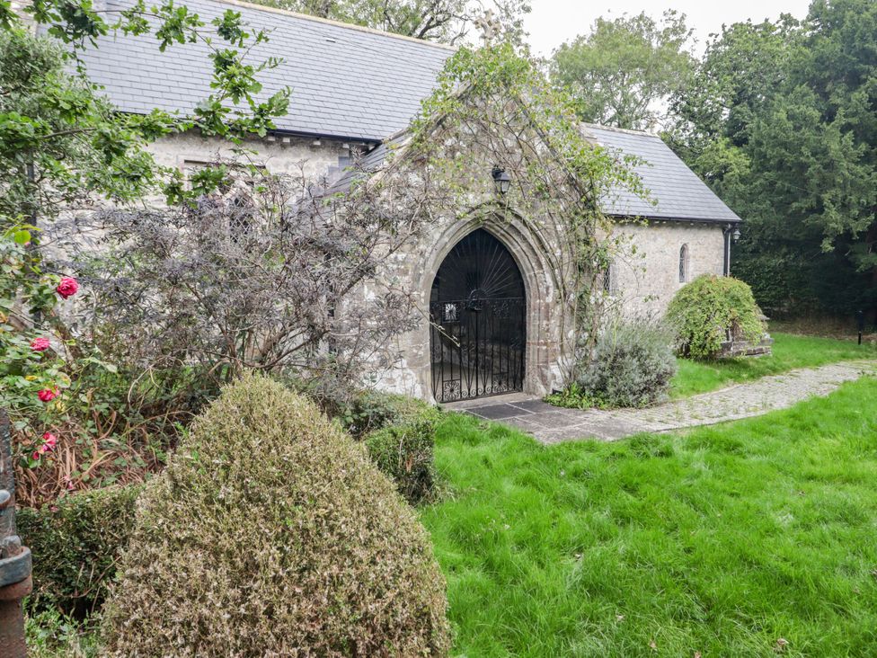 A building with a gate and path surrounded by bushes and grass at The Bakery Hotel Room Gileston near St Athan