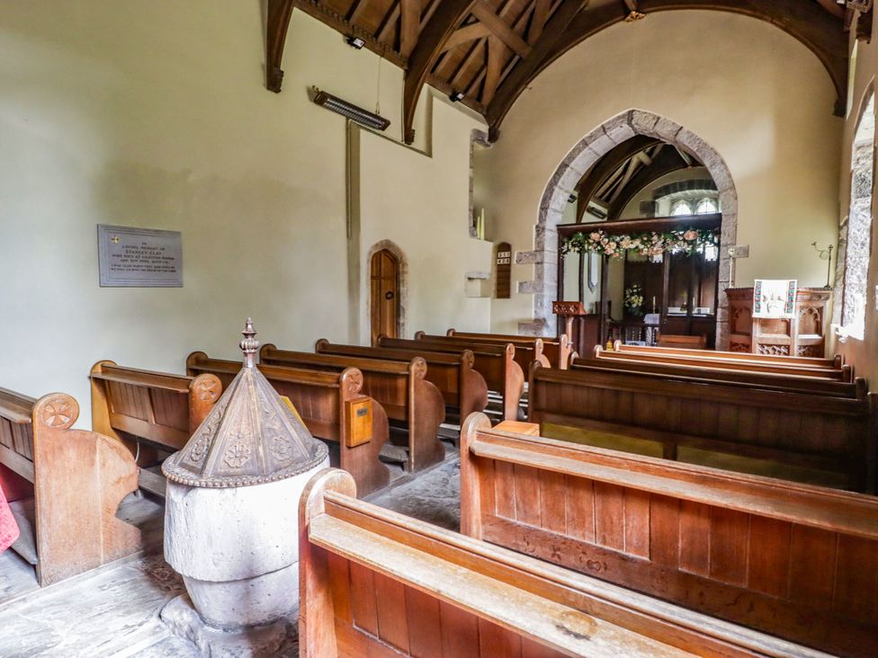A church interior with wooden pews and a font at The Bakery Hotel Room Gileston near St Athan