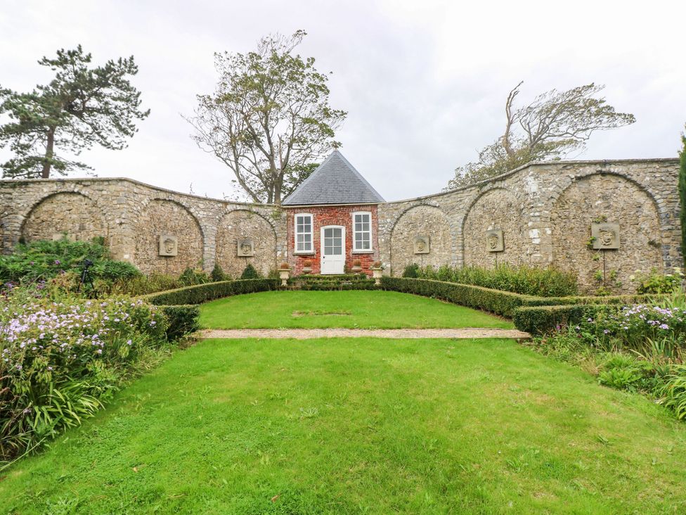A garden with a stone wall and plants at The Bakery Hotel Room in Gileston near St Athan