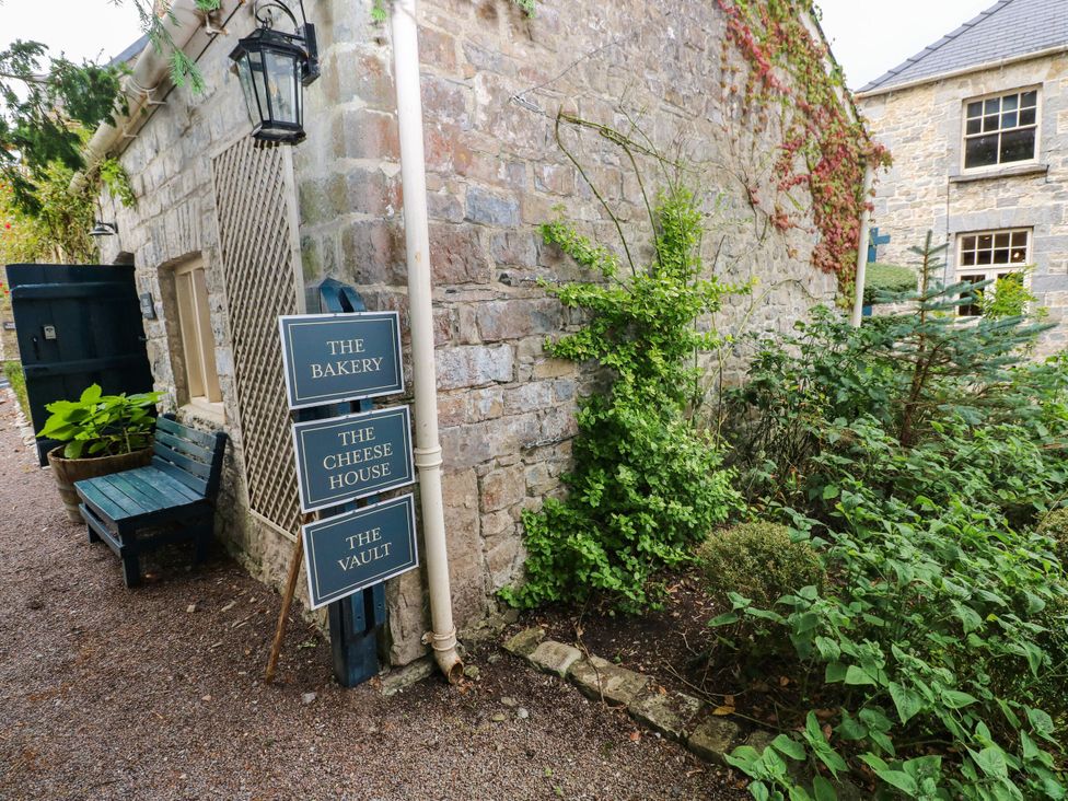 An outdoor area with signs for The Bakery, The Cheese House, and The Vault at The Bakery Hotel Room in Gileston near St Athan