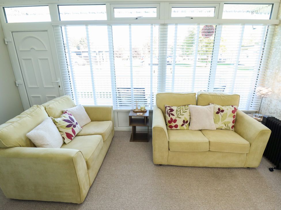 A conservatory with two sofas and a side table at Cherry Park Retreat in Skegness