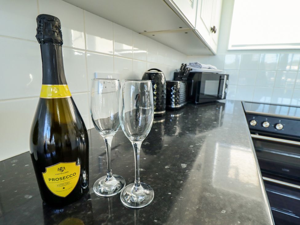 A bottle of prosecco with glasses on the countertop at Cherry Park Retreat in Skegness