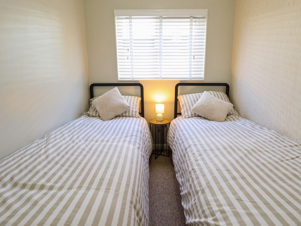 A bedroom with two single beds and a lamp at Cherry Park Retreat in Skegness