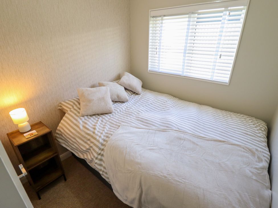A bedroom with a bed and lamp at Cherry Park Retreat in Skegness