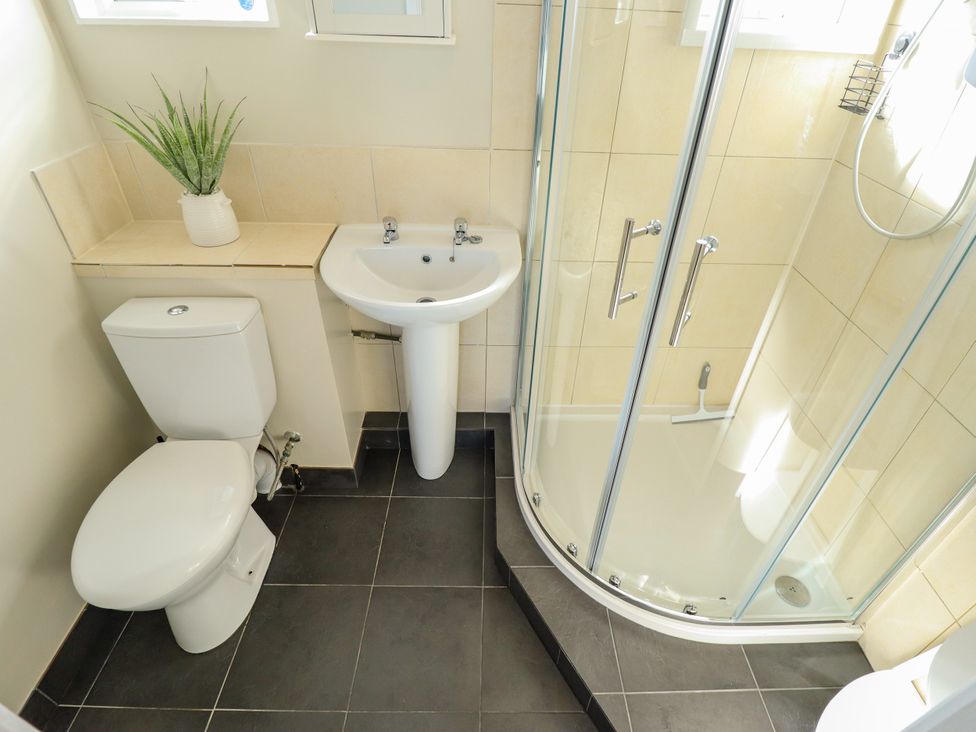 A bathroom with a toilet, sink, and shower at Cherry Park Retreat in Skegness