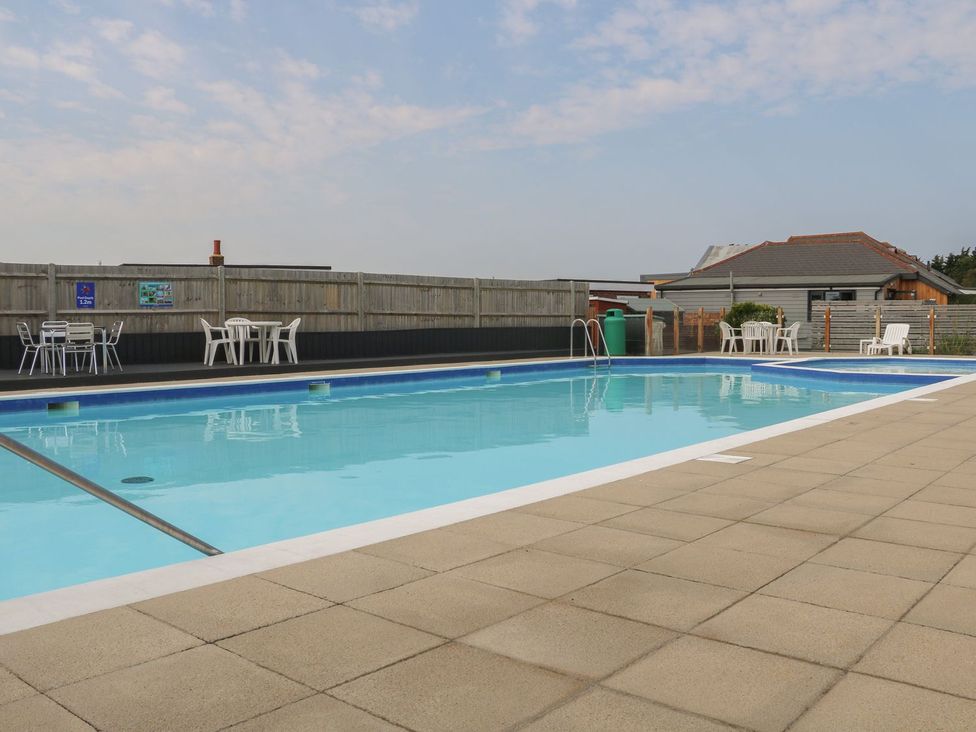An outdoor pool area with a swimming pool and deck chairs at 216 Solent Breezes in Southampton