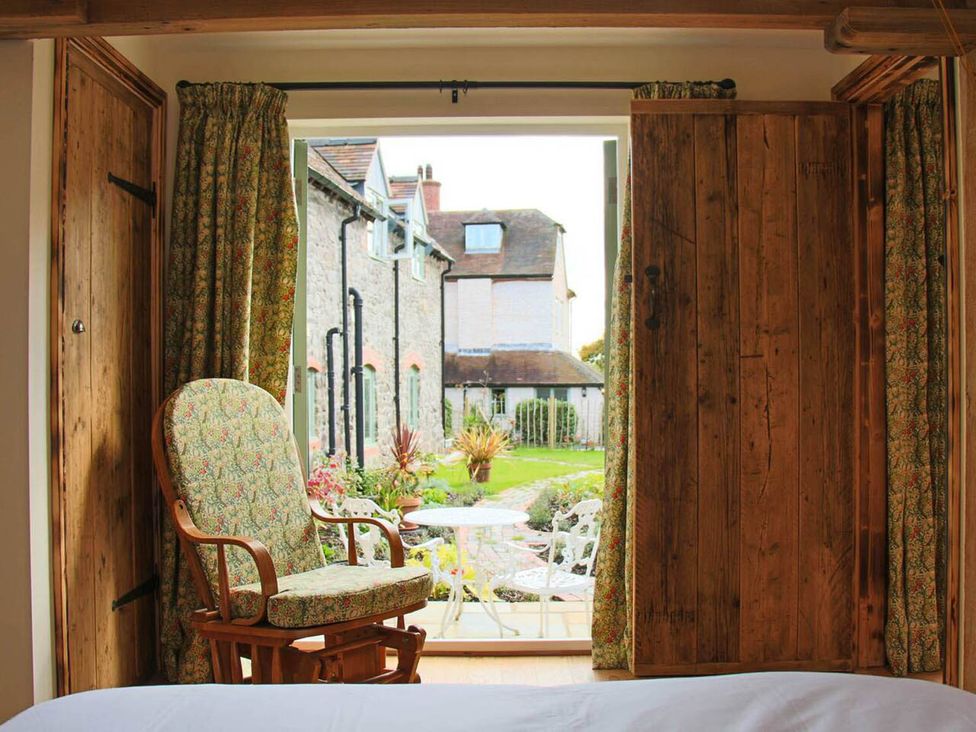 A bedroom with a rocking chair and view of the garden at Nest Holiday Hideaway Wren Cottage Stunning Area Picklescott near Church Stretton